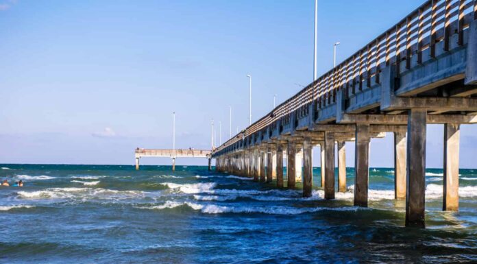 Lungo molo di pesca che si estende nel surf sulla spiaggia di Port Aransas lungo la costa nazionale di Padre Island Texas, un'isola barriera nel Golfo del Messico vicino a Corpus Christi, Texas, Stati Uniti