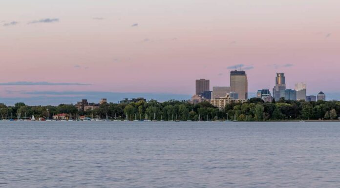 Uno scatto dello skyline di Minneapolis che si innalza sopra il lago Bde Maka Ska a South Minneapolis durante un crepuscolo estivo
