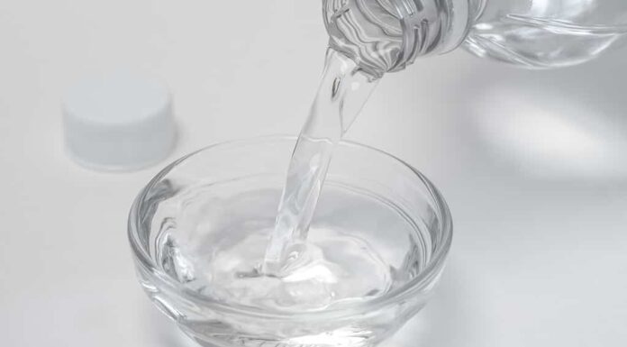 L'aceto viene versato da una bottiglia in una ciotola di vetro