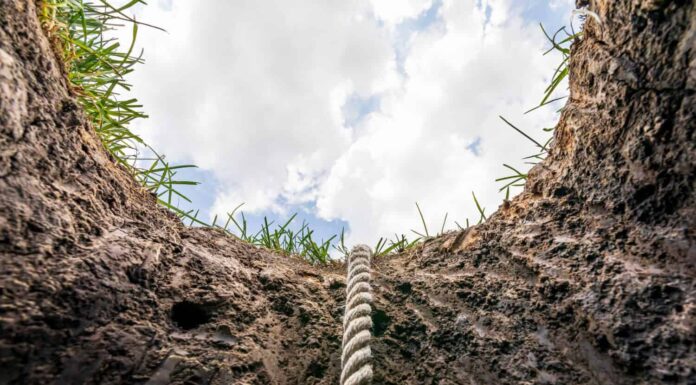 Alzando lo sguardo dal buco nel terreno con la corda.  Linea di vita, debito, concetto di aiuto per la salute mentale. 