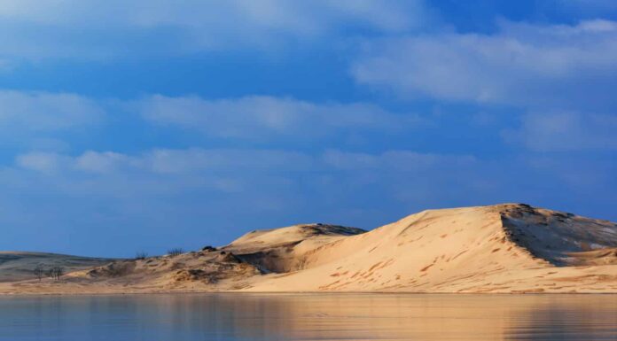 Il paesaggio invernale delle dune di sabbia del Silver Lake si riflette nel Silver Lake ghiacciato, Silver Lake state Park, Michigan, Stati Uniti 