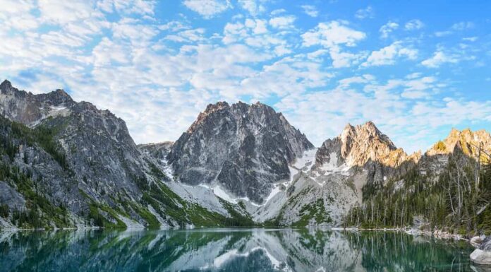 L'alba illumina Dragontail Peak, Colchuck Peak e Asgaard Pass sopra le acque Torquise del lago Colchuck.  Gli incantesimi, Cascade Mountains, Washington