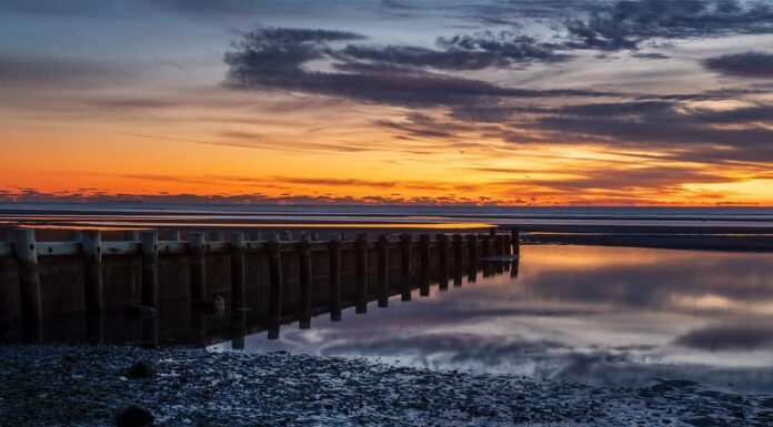 Harveys Beach in CT al tramonto.  Scattata in inverno subito dopo il tramonto su una spiaggia di Long Island Sound con un enorme cambiamento di marea.
