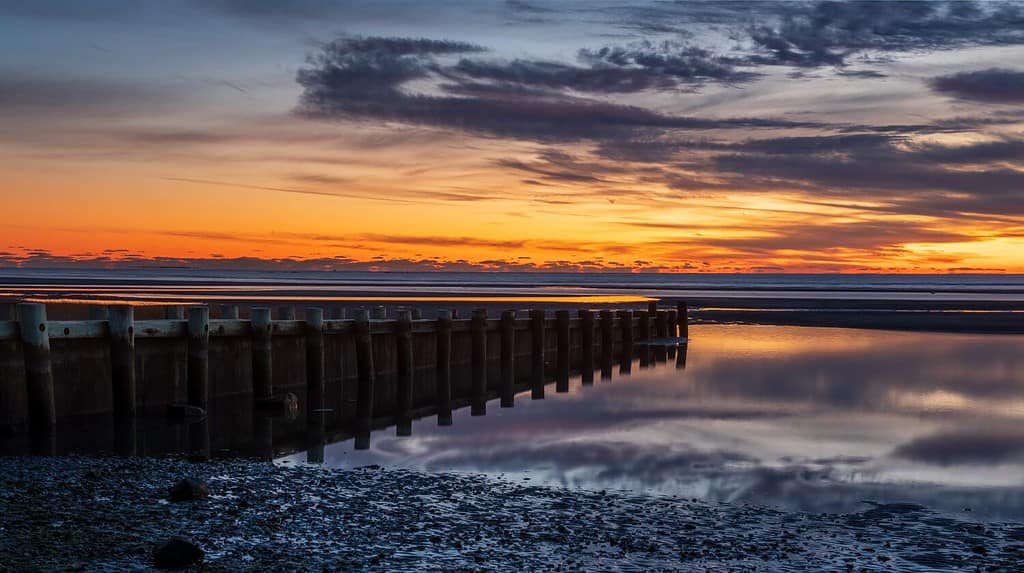Harveys Beach in CT al tramonto.  Scattata in inverno subito dopo il tramonto su una spiaggia di Long Island Sound con un enorme cambiamento di marea.