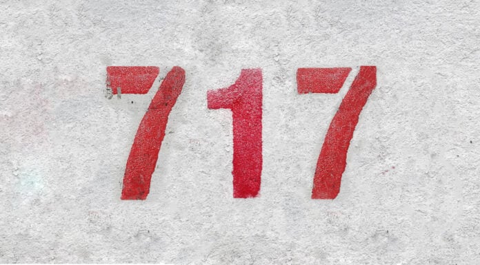 Numero rosso 717 sul muro bianco.  Vernice spray.