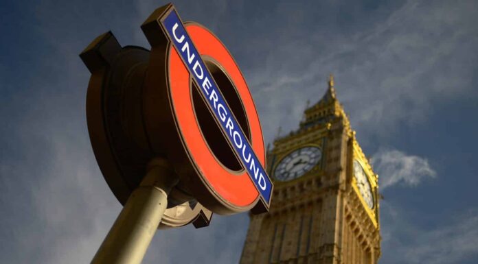Segnaletica della metropolitana di Londra e il Big Ben sotto il sole estivo