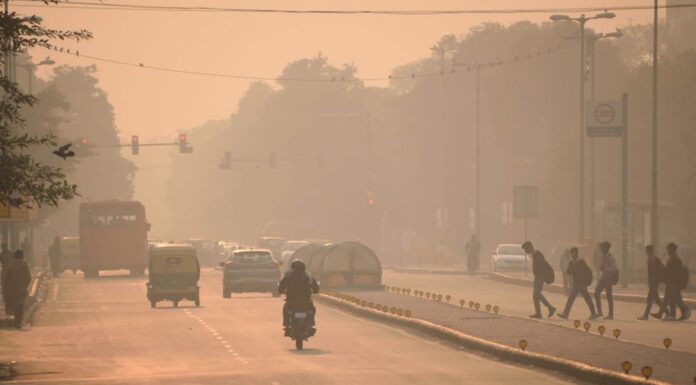 Veicoli e persone che si muovono per le strade in mezzo a un forte smog.