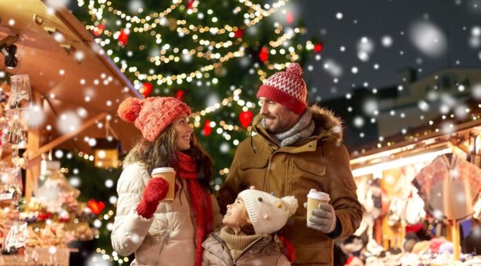 concetto di famiglia, vacanze invernali e celebrazione - madre, padre e figlia felici con bevande da asporto al mercatino di Natale sulla piazza del municipio a tallinn, in estonia, sulla neve