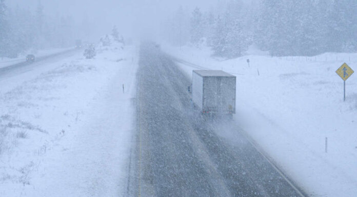 Camion e automobili si fanno strada in una bufera di neve lungo una pericolosa strada di campagna
