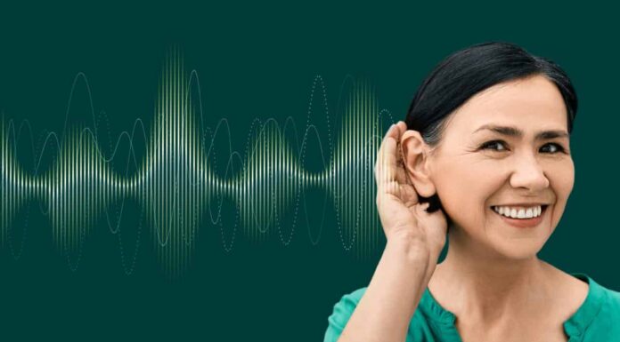 Donna positiva con la mano vicino all'orecchio e con un'onda sonora luminosa su sfondo verde che mostra una varietà di suoni diretti all'orecchio.  Concetto di salute uditiva