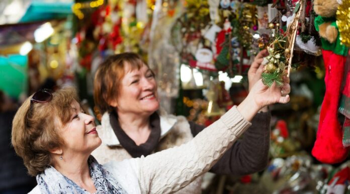Pensionate allegre che acquistano decorazioni e souvenir di Natale in fiera 