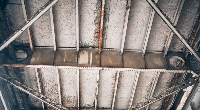 Vista dal basso verso l'alto di travi, travi e bulloni del ponte metallico.  Sovrastruttura in trave metallica rivettata.  Strutture metalliche arrugginite del ponte