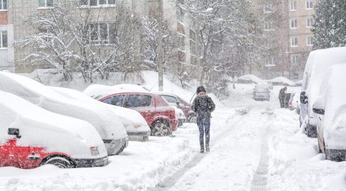 Tempesta di neve, strada innevata e auto con un pedone solitario
