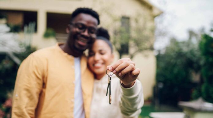 Coppia multirazziale che tiene le chiavi e sta fuori dalla loro nuova casa