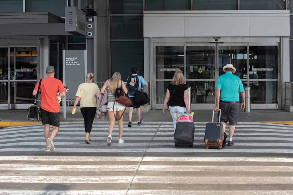 Un gruppo di passeggeri con bagagli si dirige verso l'ingresso del terminal dell'aeroporto.