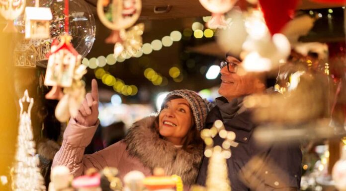 shopping, vacanze invernali e concetto di persone - coppia senior felice al negozio di souvenir del mercatino di natale sulla piazza del municipio a tallinn, estonia