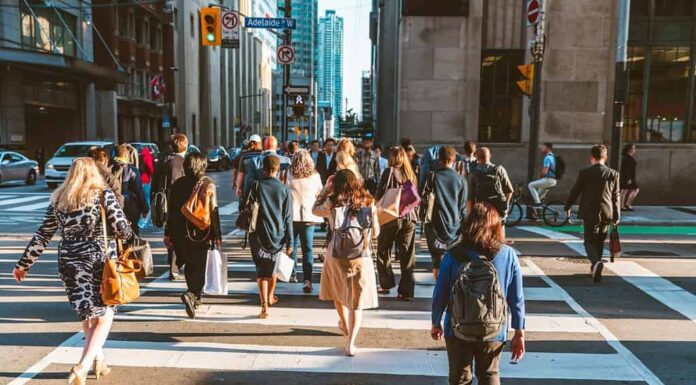 Folla di persone irriconoscibili che attraversano la strada sul semaforo zebrato nella città di Toronto all'ora di punta - Stile di vita in una grande città del Nord America