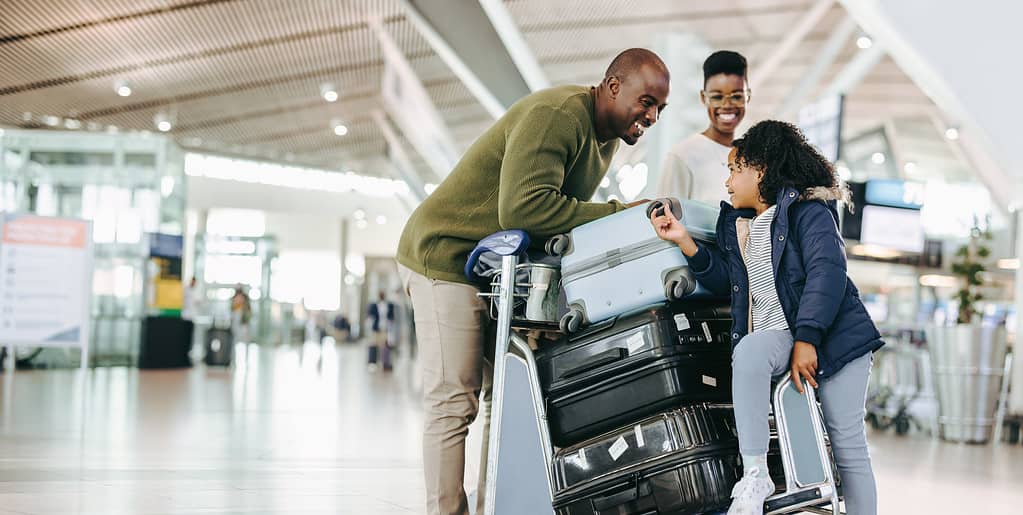 Famiglia turistica con carrello portabagagli all'aeroporto