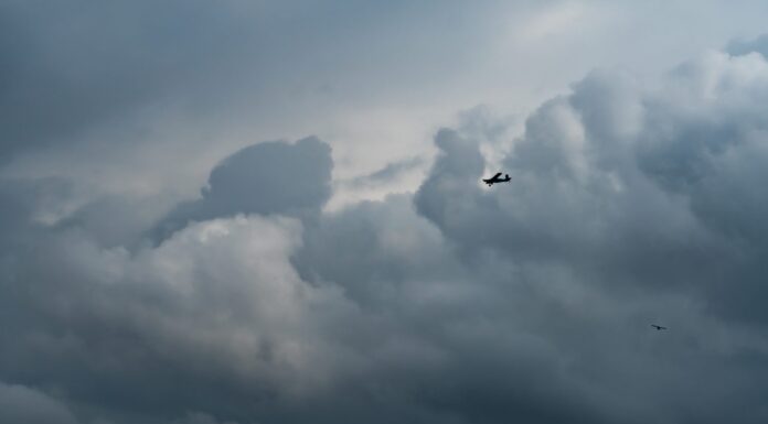 Piccolo aereo nel cielo nuvoloso per la produzione di pioggia.  Nuvole bianche e soffici con piccoli aerei per produrre piogge artificiali.  Due aerei che volano sul cielo nuvoloso.  Aereo agricolo per precipitazioni artificiali.