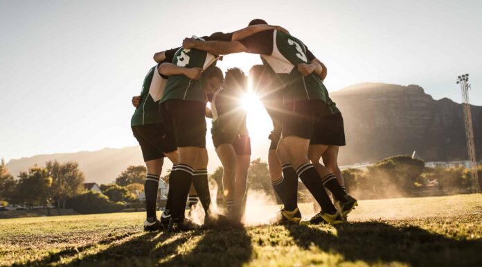 Squadra di rugby in piedi in una calca e strofinando i piedi a terra.  Squadra di rugby che celebra la vittoria.