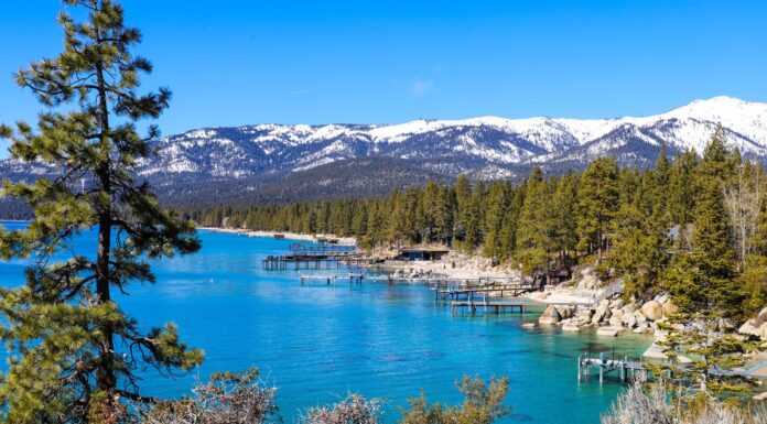 uno splendido paesaggio invernale con acque cristalline del lago, catene montuose innevate e rigogliosi alberi verdi lungo le rive del lago e cielo azzurro al Lake Tahoe nel Nevada State Park a Incline Village	
