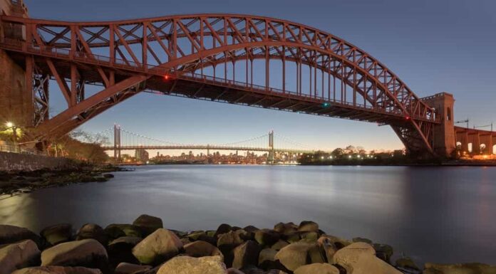 New York, New York, Stati Uniti d'America al Hell Gate Bridge al tramonto sull'East River al crepuscolo.