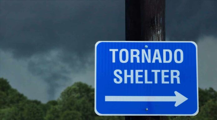 Cartello per rifugio tornado con una piccola nuvola a imbuto sullo sfondo - concetto di pericolo immediato in condizioni meteorologiche avverse e in cerca di riparo