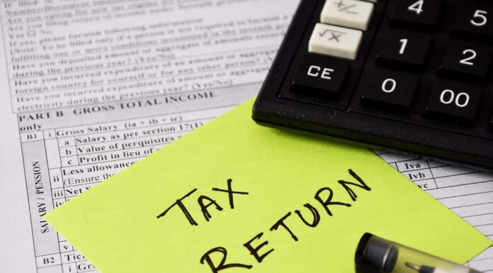 Nota adesiva con il testo scritto a mano DICHIARAZIONE FISCALE inserito nel modulo di presentazione della dichiarazione dei redditi.  Messa a fuoco selettiva sul testo.