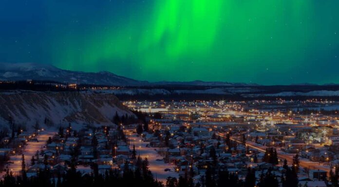 Forte tempesta di aurora boreale (Aurora boreale) nel cielo notturno sopra il centro di Whitehorse, capitale del territorio dello Yukon, Canada, in inverno.
