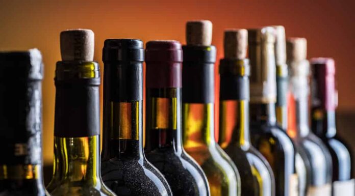 Bottiglie di vino tappate e stappate in primo piano in linea.  Sfondo di vino.