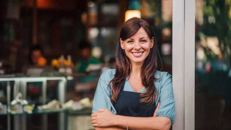 Happy cafe owner stands outside her pest-free business. Learn how to pest-proof your business with these tips from Xceptional Wildlife.