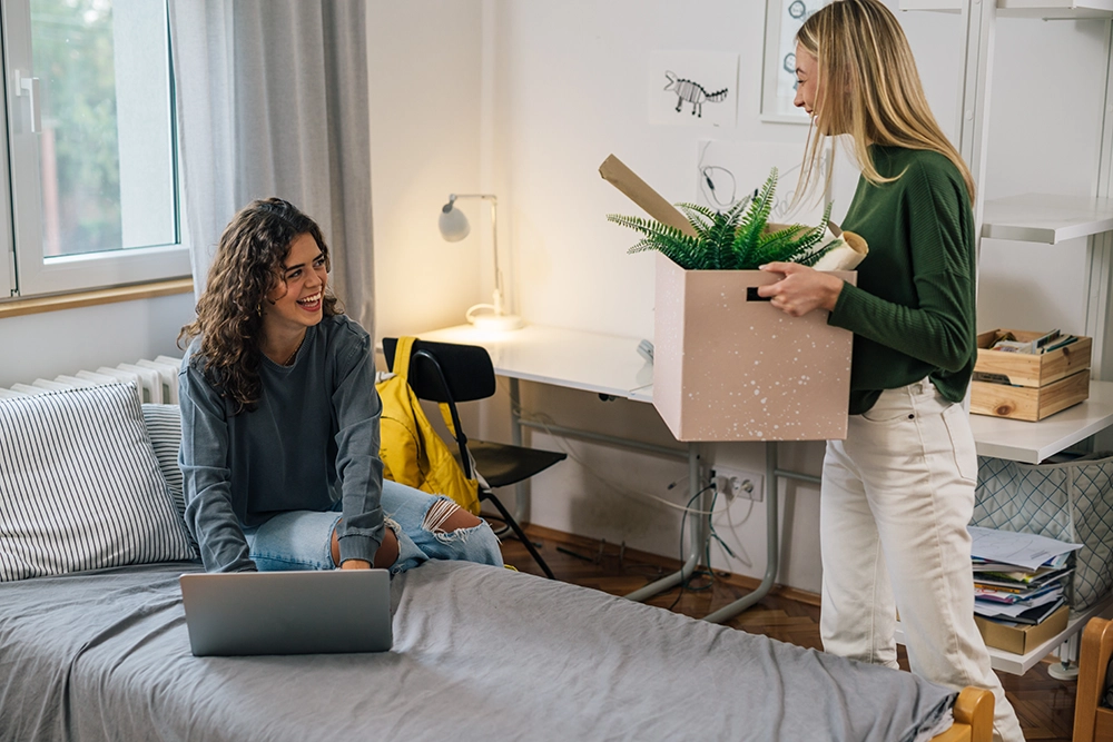Two female college students smile as they move into their new dorm.