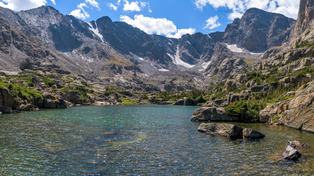 Lake of Glass - Una vista panoramica del limpido e colorato Lake of Glass circondato da aspre vette del Continental Divide in una soleggiata giornata estiva.  Parco Nazionale delle Montagne Rocciose, Colorado, Stati Uniti d'America.