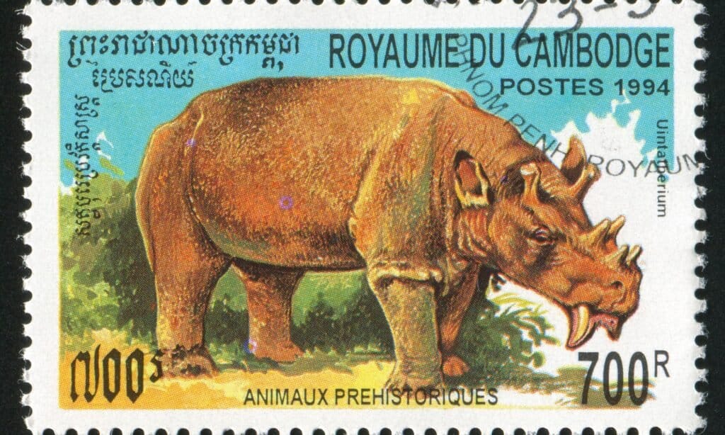 Un francobollo stampato dalla Cambogia mostra animali preistorici.  Uintatherium era un erbivoro e sembrava essersi specializzato in piante acquatiche.