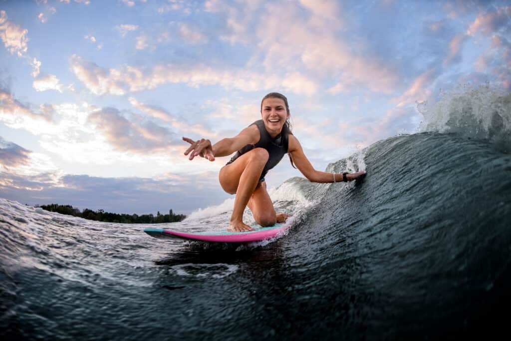Giovane donna che pratica il surfing sulla tavola da surf rosa