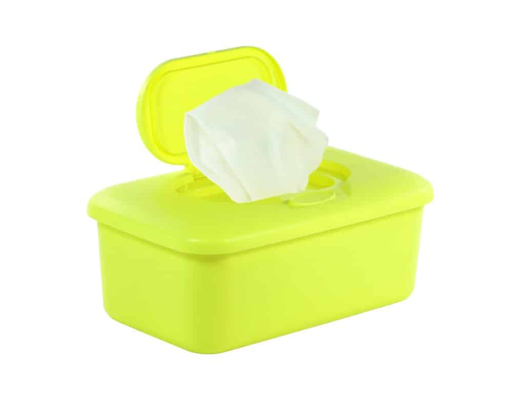 Un contenitore pop-up in plastica giallo neon di salviette per neonati con una salvietta bianca pronta.  Sfondo bianco. 