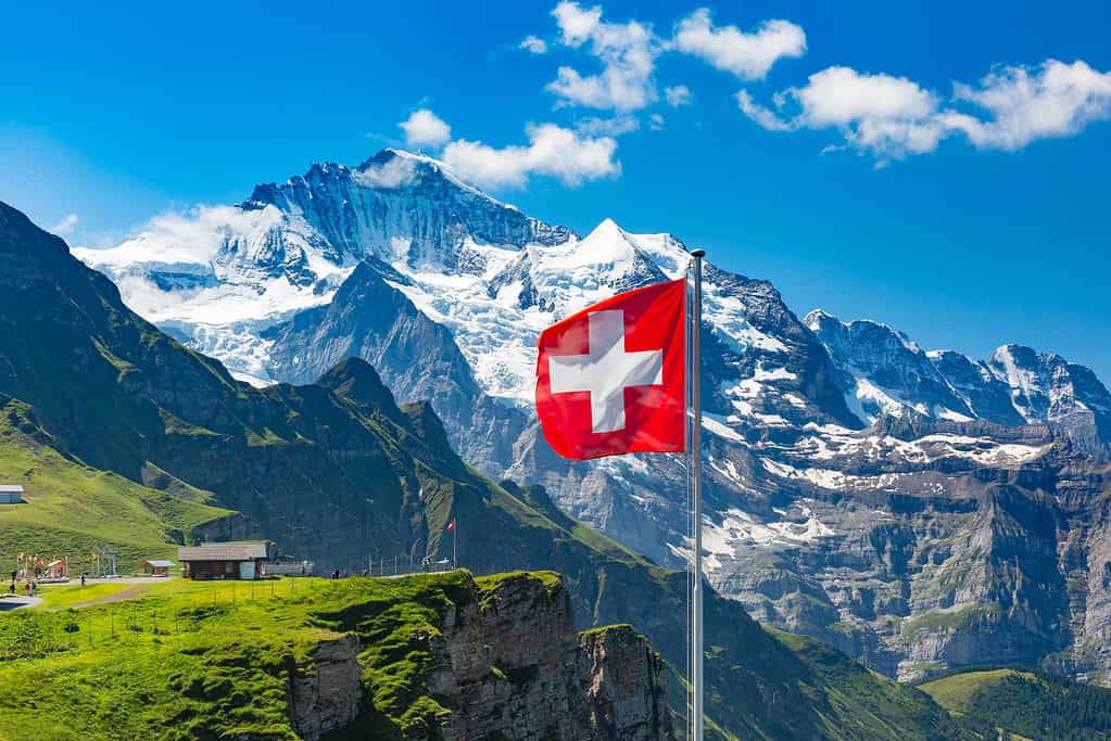 Bandiera svizzera che ondeggia su un picco di montagna in Svizzera