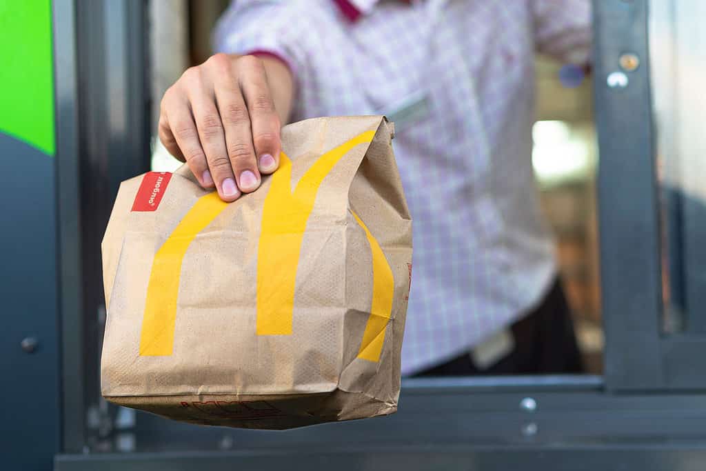 L'uomo porge un sacchetto di fast food fuori dalla finestra del drive-thru