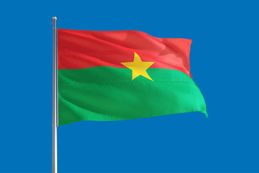 Bandiera del Burkina Faso vola contro un cielo blu senza nuvole