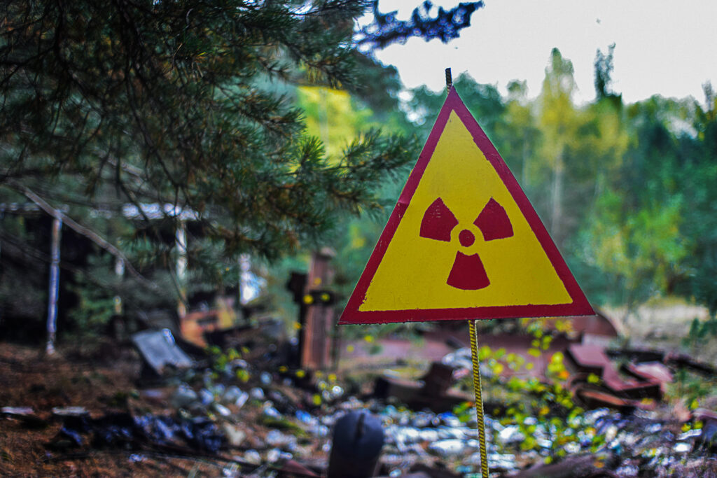 il segnale di radiazione triangolare giallo-rosso sullo sfondo dei rifiuti radioattivi avverte i lavoratori della discarica del pericolo di infezione da radiazioni