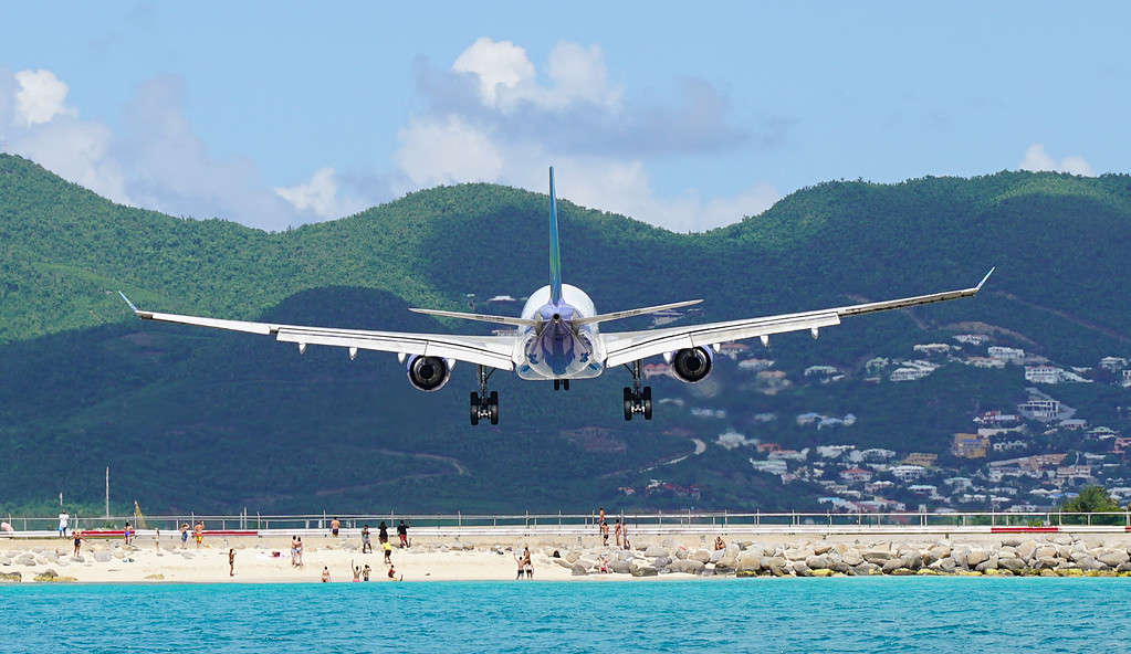 Aereo che sorvola le persone durante l'atterraggio a Maho Beach a Saint Maarten all'aeroporto Princess Juliana.