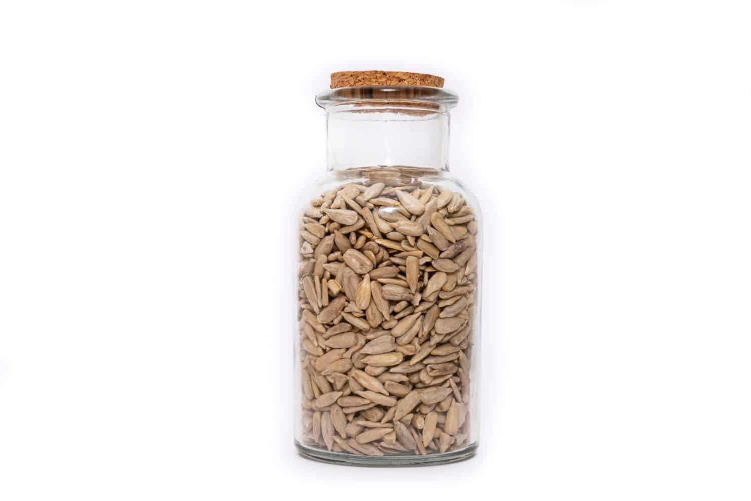 Un barattolo di semi di girasole essiccati isolati su sfondo bianco, semi nutrienti essiccati e conservati.  Scelta di cibi sani.