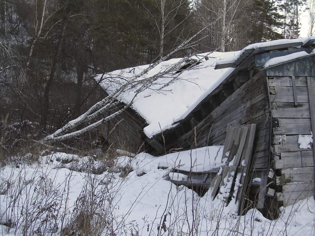 Casa fatiscente decrepita.  Fondo rustico del grunge.  Una baracca crollata nella neve.