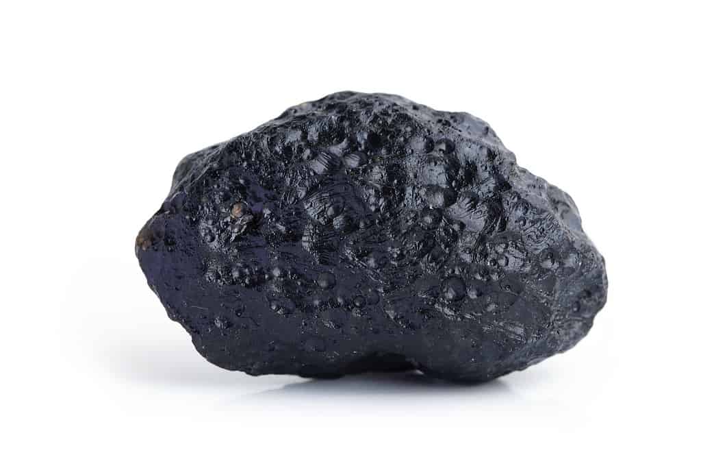 Roccia di pietra nera meteorite isolata su sfondo bianco.