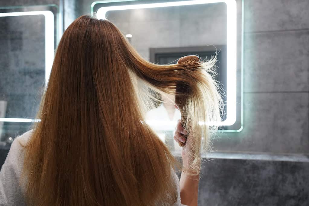 Donna davanti allo specchio che spazzola i capelli