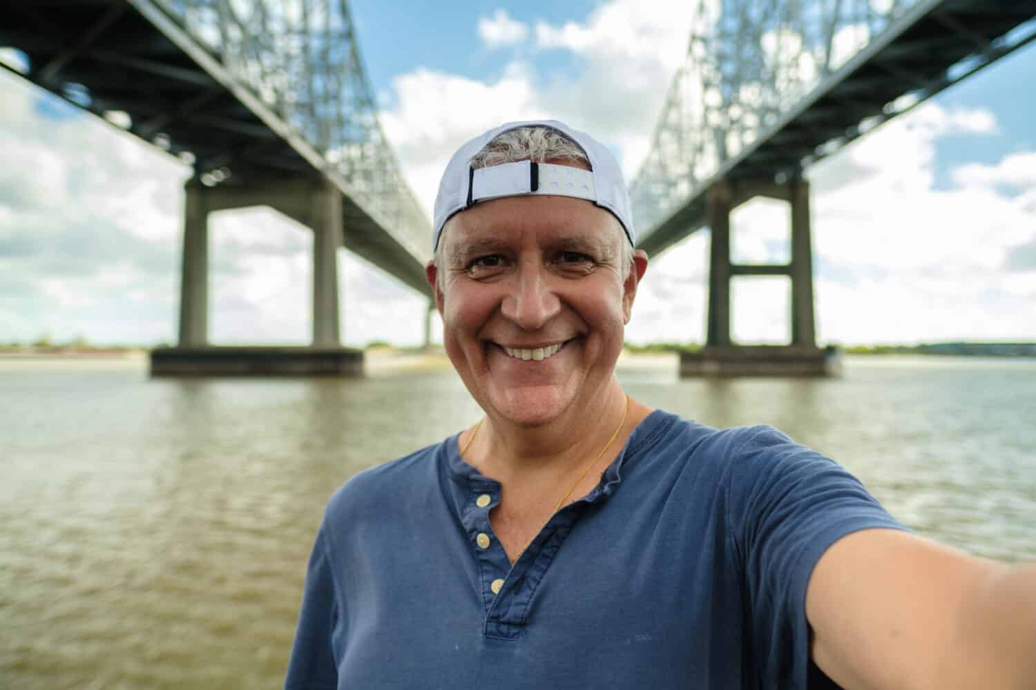 Bell'uomo anziano che si fa un selfie lungo il fiume Mississippi e il ponte a New Orleans, Louisiana.