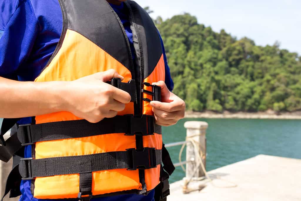 Giovane viaggiatore che indossa un giubbotto di salvataggio prima di salire sulla barca in vacanza