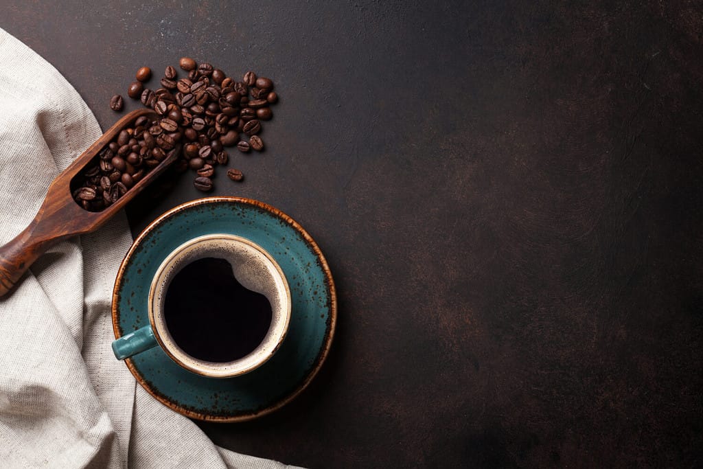 Tazza di caffè e fagioli sul vecchio tavolo da cucina.  Vista dall'alto con copyspace per il tuo testo