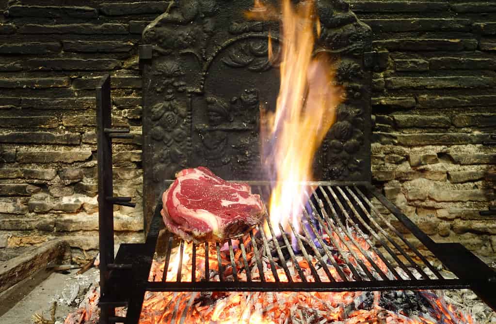 Le bistecche di costolette (cote de boeuf) vengono grigliate su un fuoco aperto