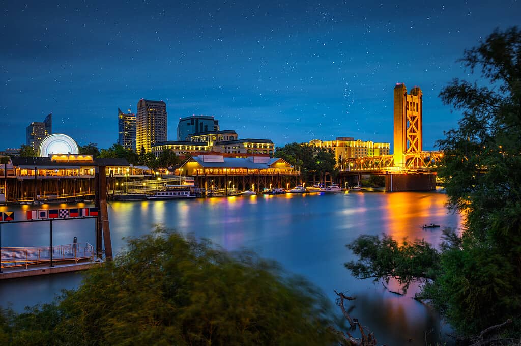 Il Gold Tower Bridge e il fiume Sacramento a Sacramento, California, fotografati dal River Walk Park di notte con le stelle nel cielo.